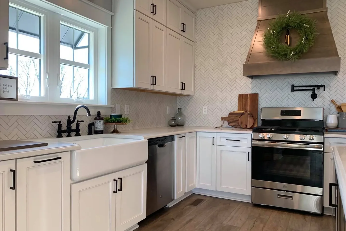 A finished Beracah kitchen with white shaker cabinets, a farmhouse sink and a herringbone backsplash.
