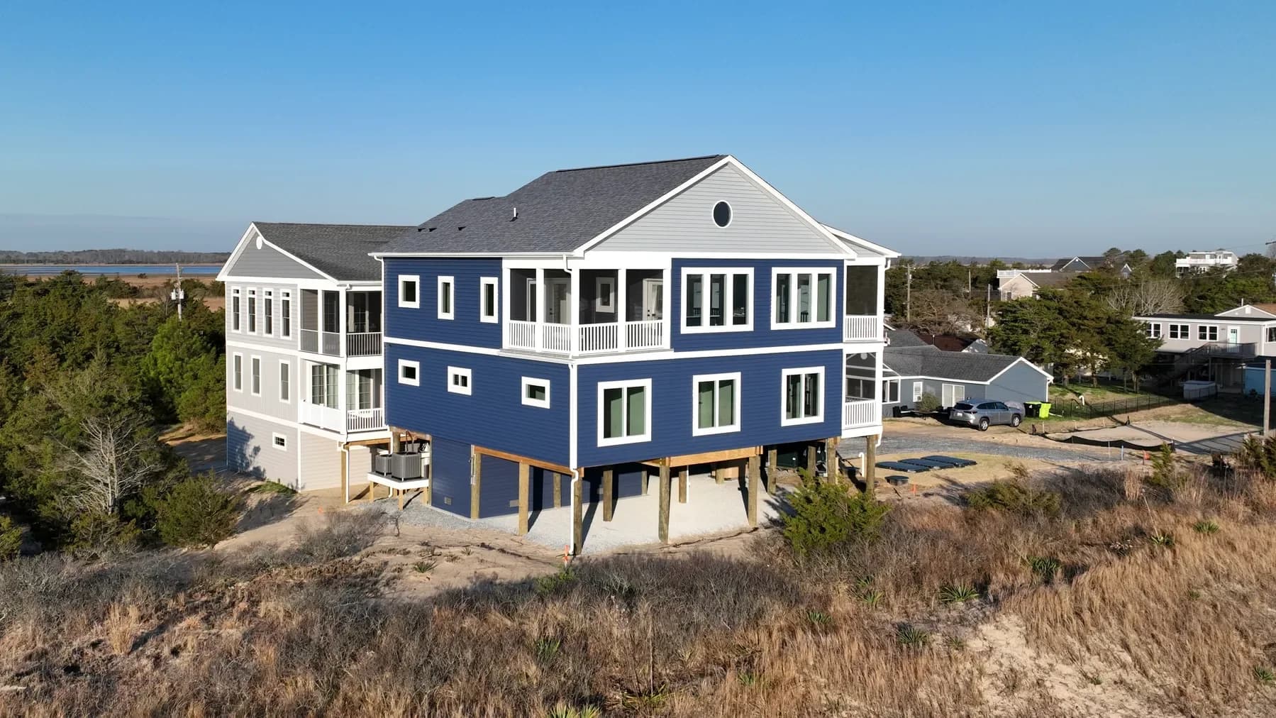 A navy-sided Beracah home on pilings above the dune grass, looking back toward the bay on the Delaware coast.