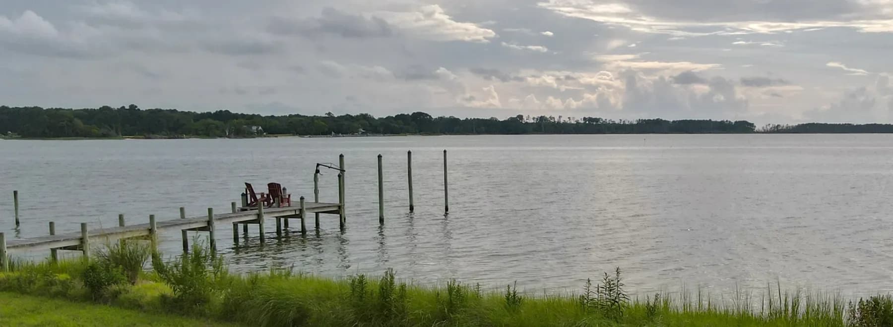 An open waterfront lot on the Delmarva bay side, with a weathered pier running out into the shallows.